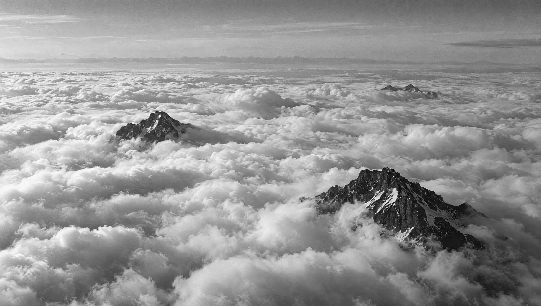 A sea of cloud with dark peaks breaking through.